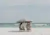 two people under beach umbrella near shoreline