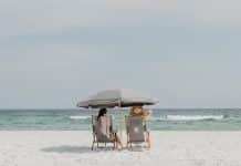 two people under beach umbrella near shoreline