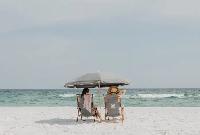 two people under beach umbrella near shoreline