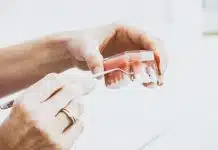 person wearing silver-colored ring while holding denture